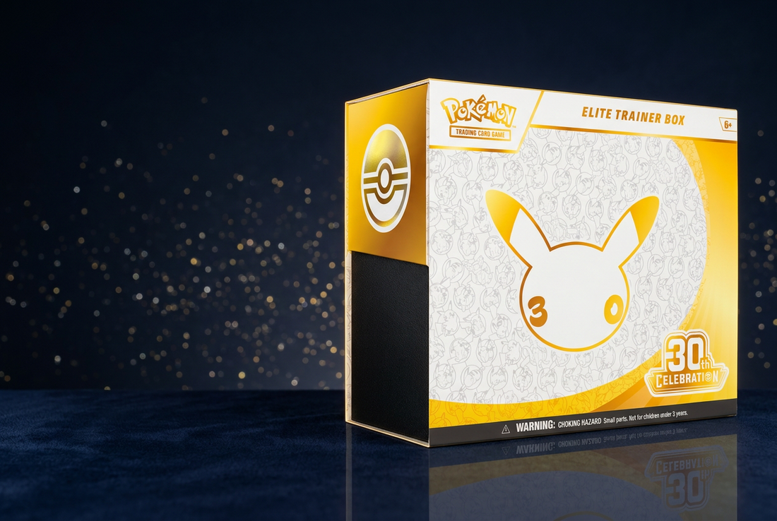 White and gold Pokémon 30th Celebration Elite Trainer Box on a dark tabletop with warm anniversary-inspired lighting.